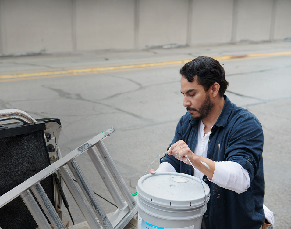 guy getting a 5-gallon paint bucket out of truck.