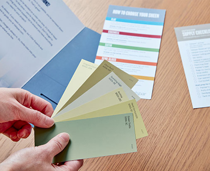 Mano que sostiene muestras de color junto a un folleto de colores abierto