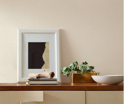 Neutral wall and cabinet with wood surface and an array of artwork and décor. 