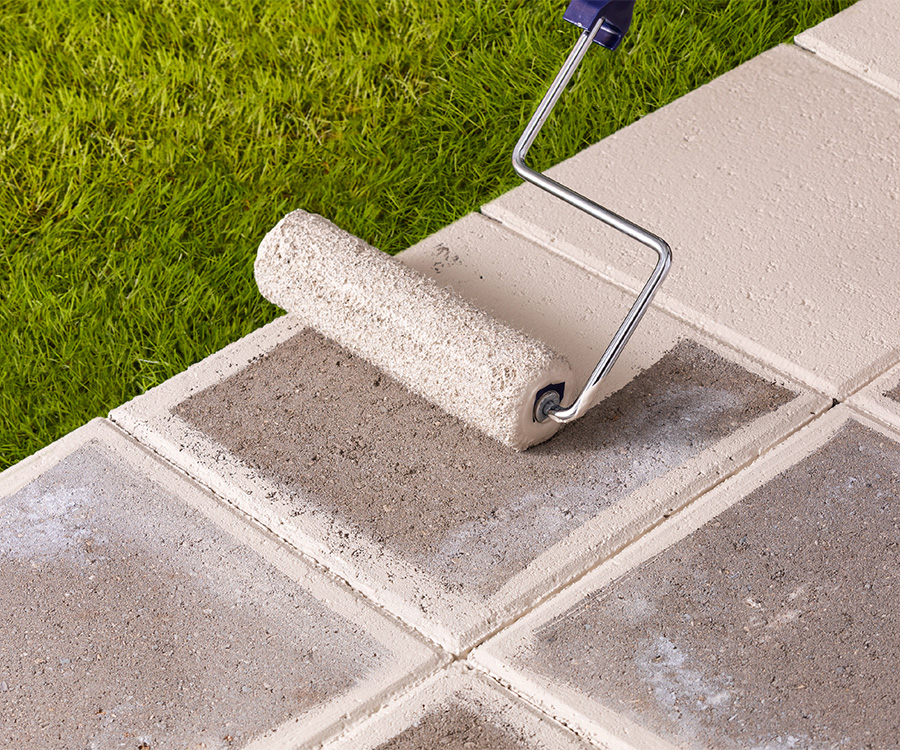 Pasillo de concreto en césped sellado con rodillo con sellador blanco.
