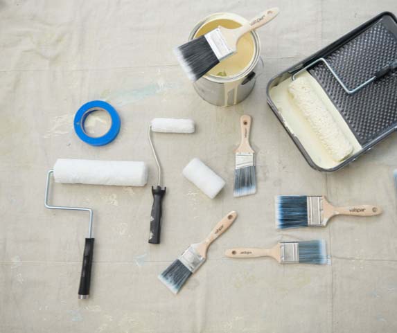 surtido de suministros de pintura: brochas, rodillos, cinta, pintura
