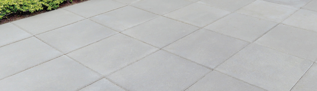 Pasillo de concreto en el exterior o superficie de patio con secciones cuadradas.